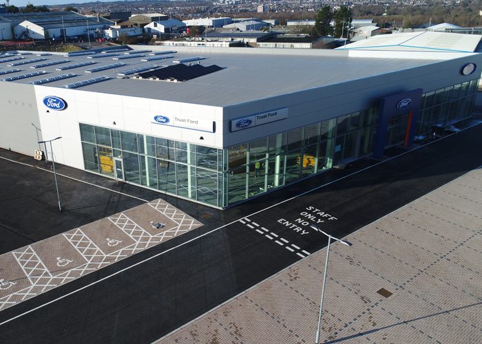 A sunny, aerial view of the TrustFord garage showroom in Aberdeen, with steel construction and cladding installation by KR Group. Showing the Ford logo and entrance to the building.