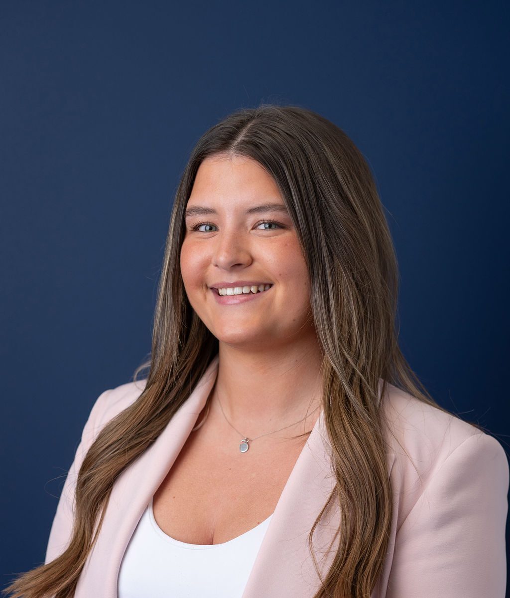 Trades Awards nominee, and KR Group team member, Caitlin Bremner standing and smiling against blue background.