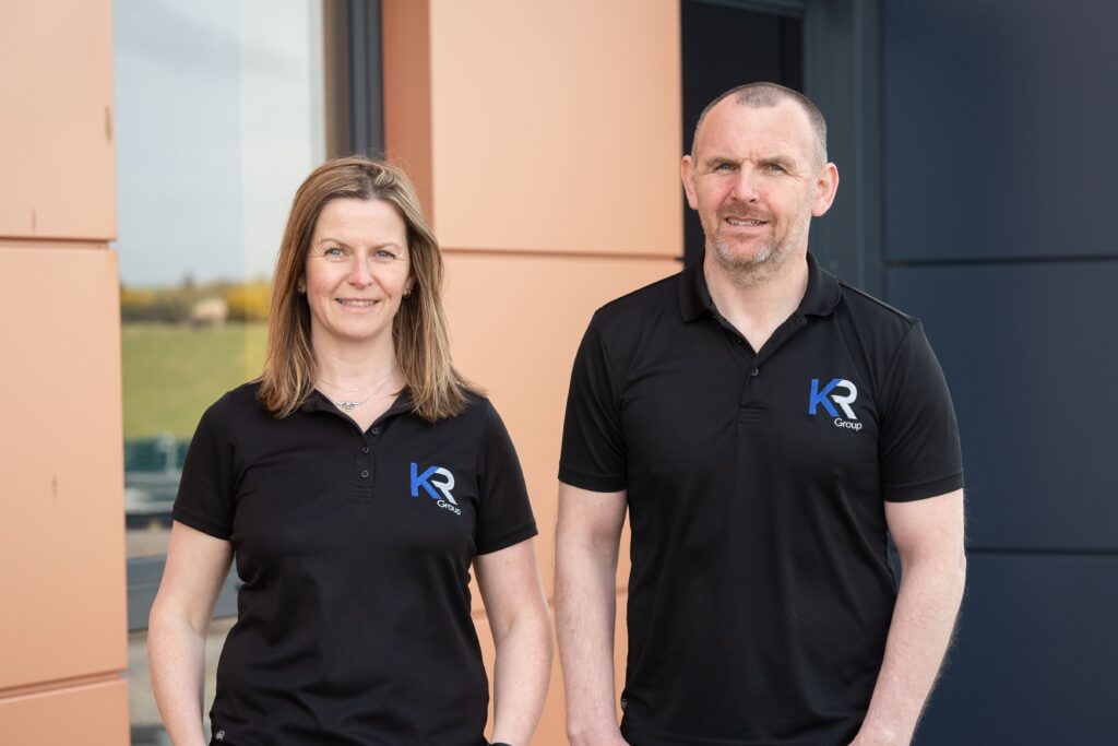 VIBES award finalists, KR Group's Business Director, Nicola Fraser and Managing Director, Kenny Robertson, standing side by side in front of the KR Group headquarters in Newburgh, Aberdeenshire.