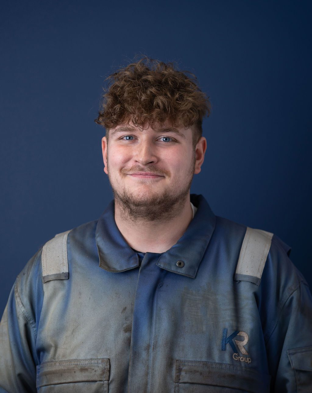 KR Group workshop trainee smiling in photo, wearing a blue boiler suit.