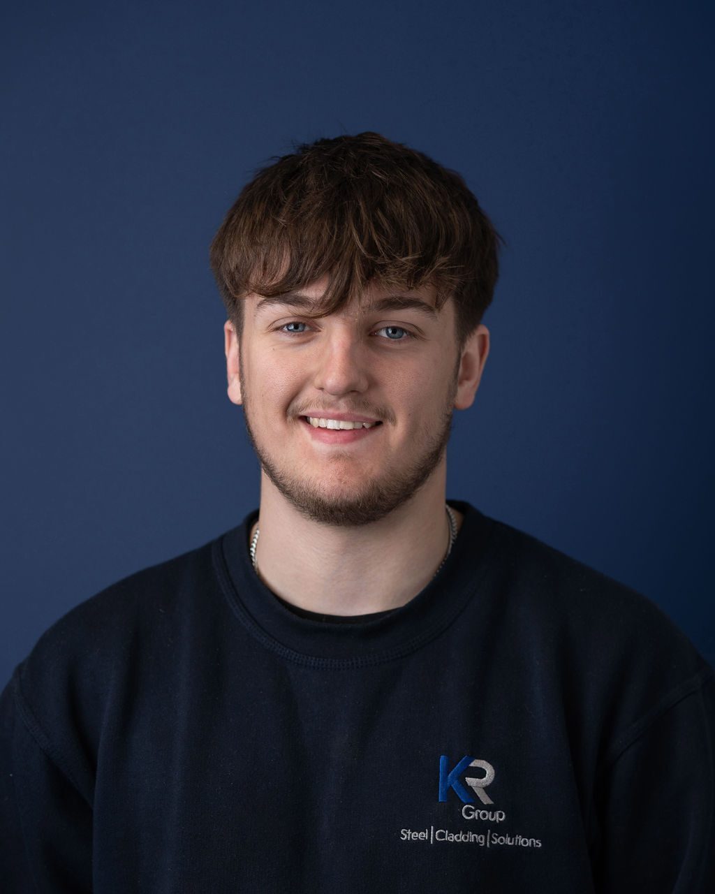 KR Group workshop trainee smiling in photo, wearing a blue boiler suit.