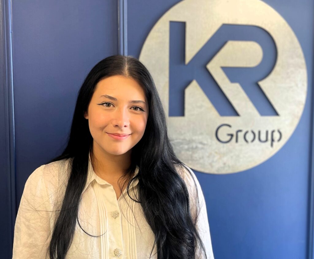 Headshot image of Jennie Innes, Marketing Assistant at KR Group Scotland standing against a blue background with the KR logo.