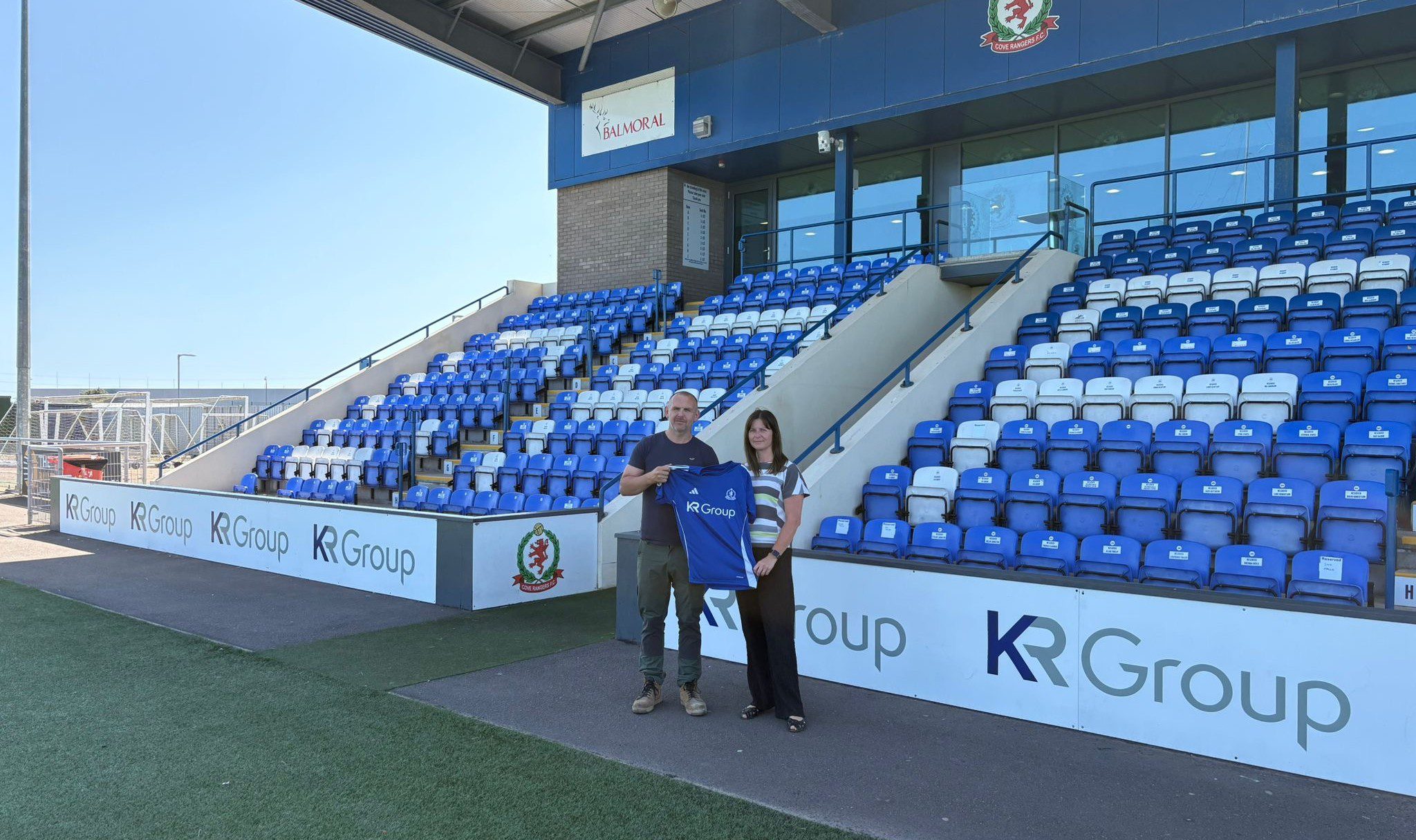 KR Group Scotland directors, Kenny Robertson and Nicola Fraser standing on the pitch at Balmoral Stadium in Aberdeen holding the new KR Group sponsored strip.