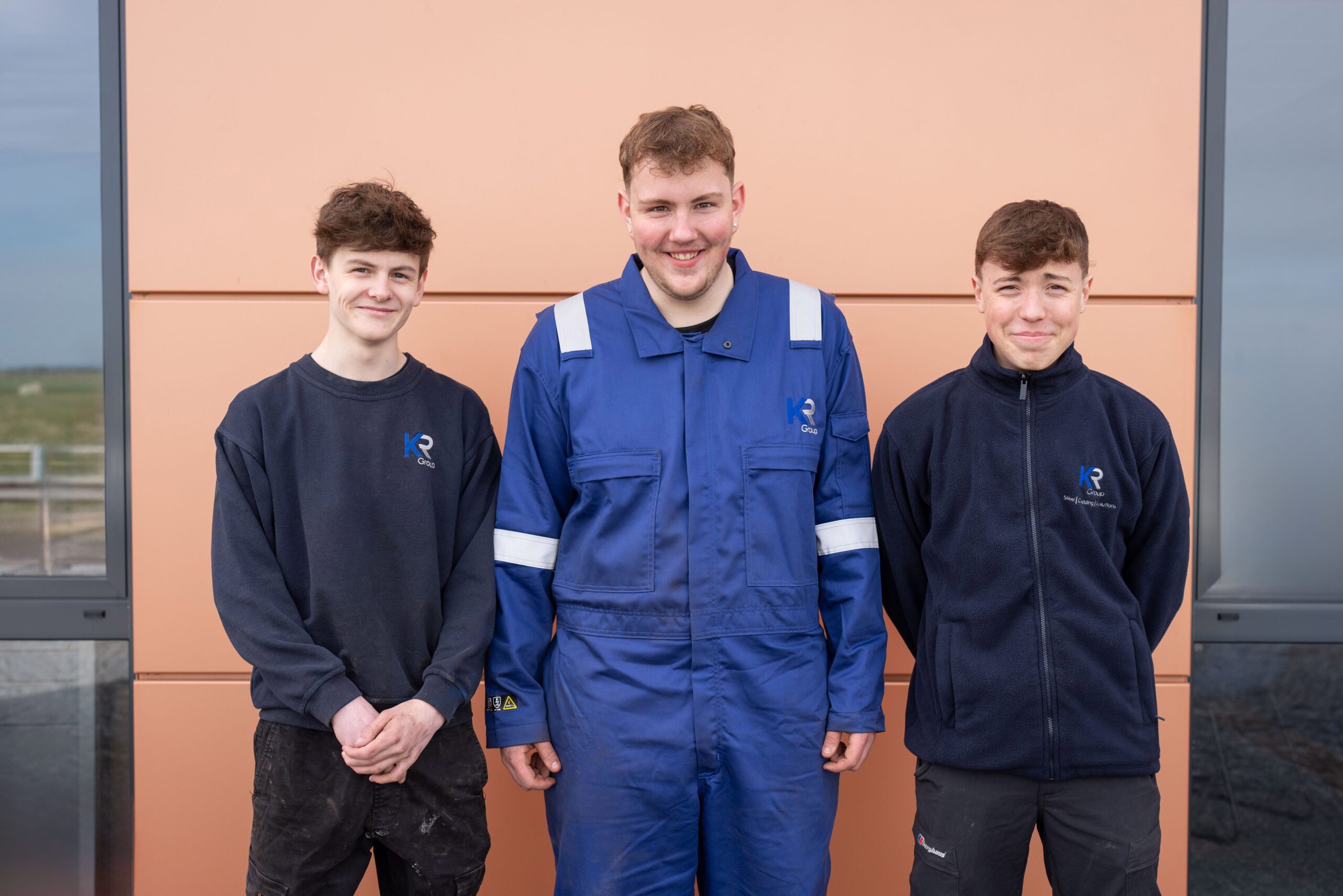 Three KRedit trainees standing and smiling outside KR Group Scotland's offices in Aberdeenshire.